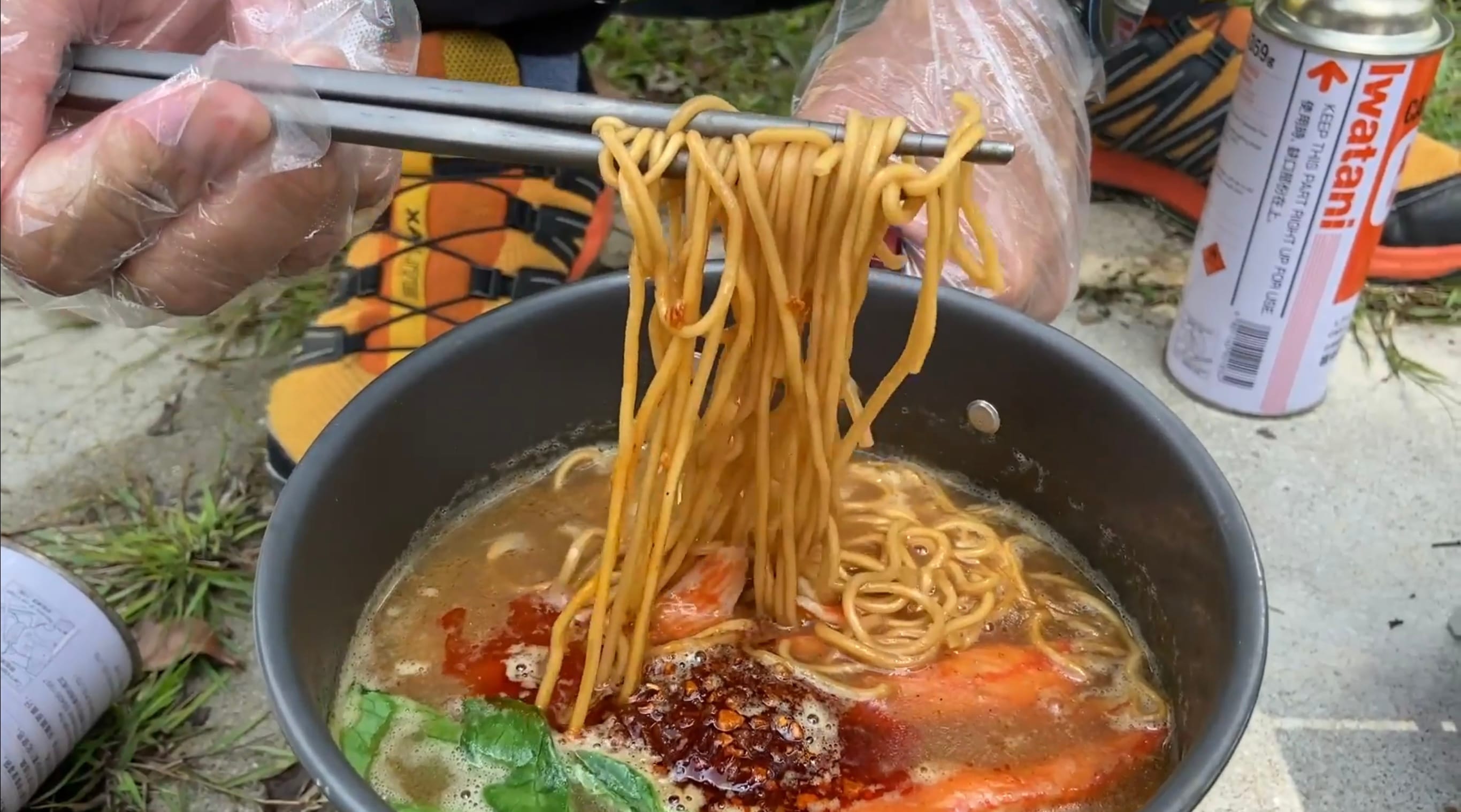 Cooking a pot of prawn noodles outdoors.